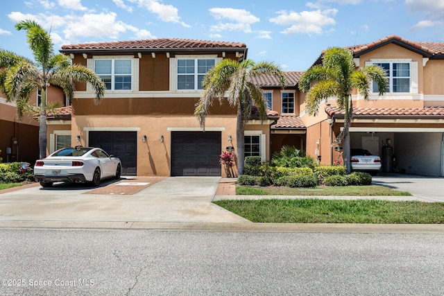 multi unit property featuring a tile roof, driveway, and stucco siding