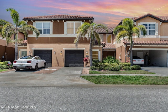 townhome / multi-family property featuring a tile roof and driveway