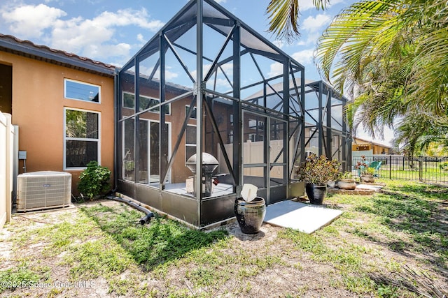 back of house featuring glass enclosure, central air condition unit, a fenced backyard, a patio, and stucco siding