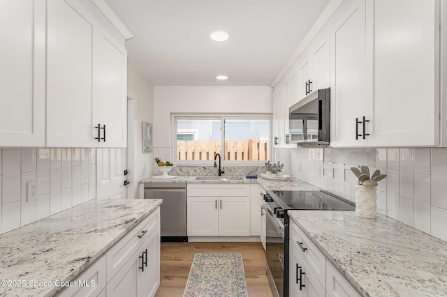225 Price Ct, Satellite Beach, FL 32937 - kitchen featuring appliances with stainless steel finishes, a sink, white cabinetry, light wood finished floors, and recessed lighting