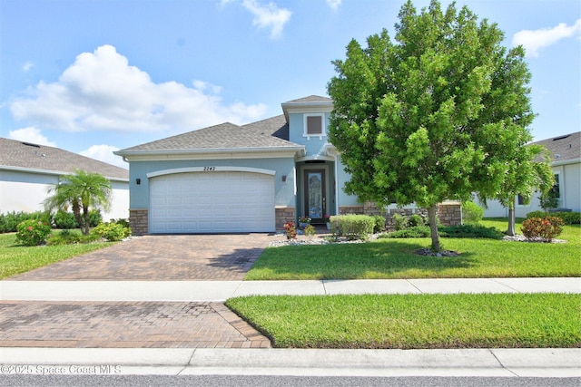 2242 Great Belt Cir, Melbourne, FL 32940 - view of front of house featuring a garage, decorative driveway, a front yard, stucco siding, and stone siding