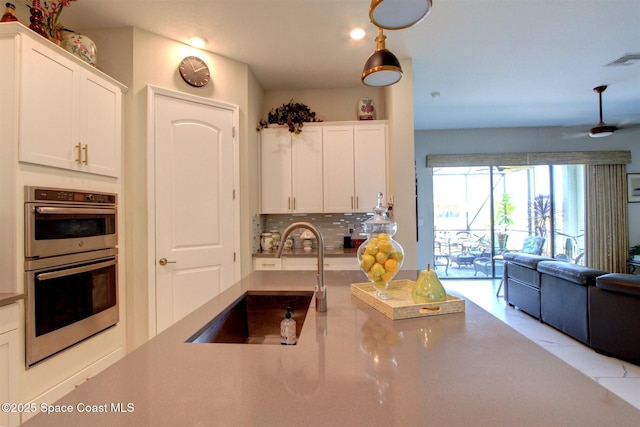 2242 Great Belt Cir, Melbourne, FL 32940 - kitchen with a sink, stainless steel double oven, open floor plan, and white cabinets