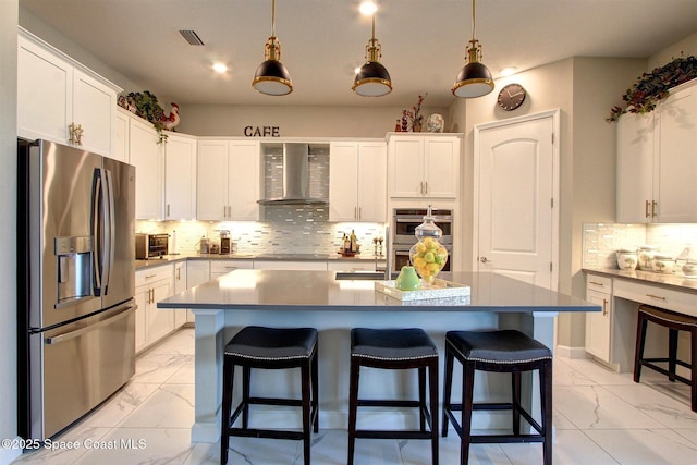 2242 Great Belt Cir, Melbourne, FL 32940 - kitchen featuring appliances with stainless steel finishes, wall chimney exhaust hood, light marble finish floors, a kitchen bar, and white cabinetry