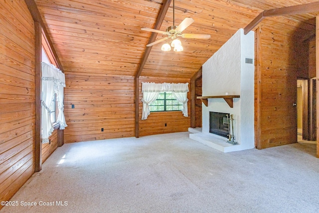 unfurnished living room with wooden ceiling, carpet, wooden walls, a fireplace with raised hearth, and ceiling fan
