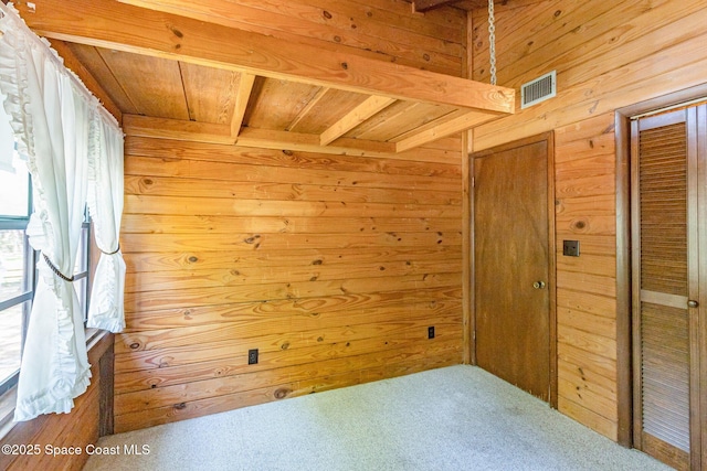 carpeted spare room with wooden walls, wooden ceiling, and beamed ceiling
