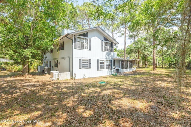 rear view of property featuring central AC unit and a sunroom