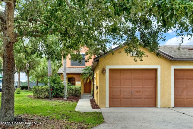 townhome / multi-family property with stucco siding, concrete driveway, an attached garage, and a front lawn