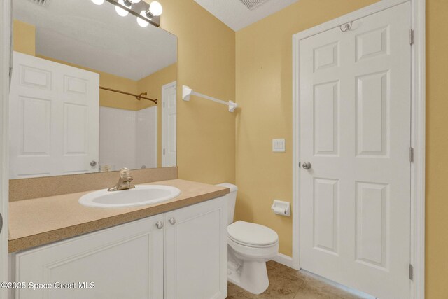 bathroom with toilet, vanity, and tile patterned floors