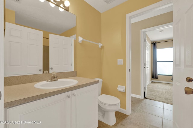 bathroom featuring toilet, vanity, tile patterned floors, and baseboards