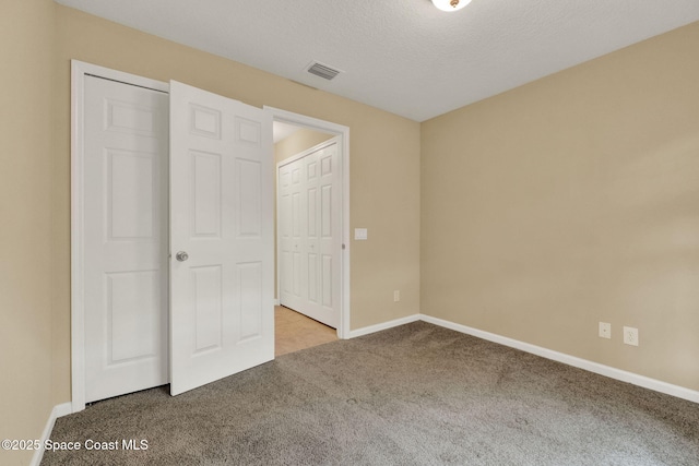 unfurnished bedroom featuring carpet, baseboards, and a textured ceiling