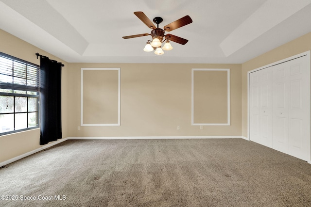 unfurnished bedroom with a raised ceiling, carpet, and baseboards