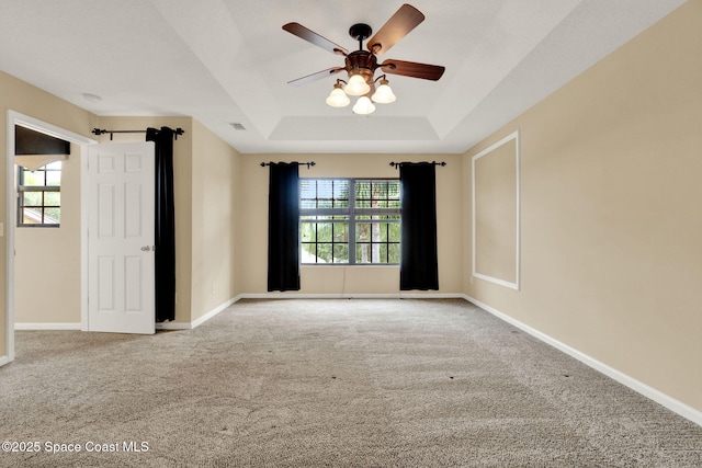 unfurnished room featuring a tray ceiling, a ceiling fan, carpet flooring, and baseboards