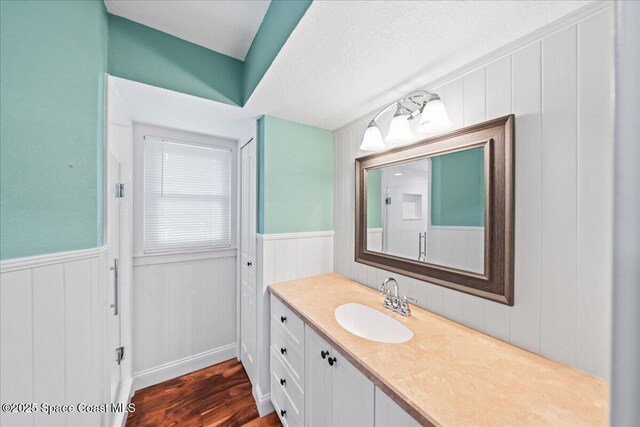 6345 Anchor Ln, Rockledge, FL 32955 - full bathroom featuring vanity, a wainscoted wall, wood finished floors, a shower, and a decorative wall