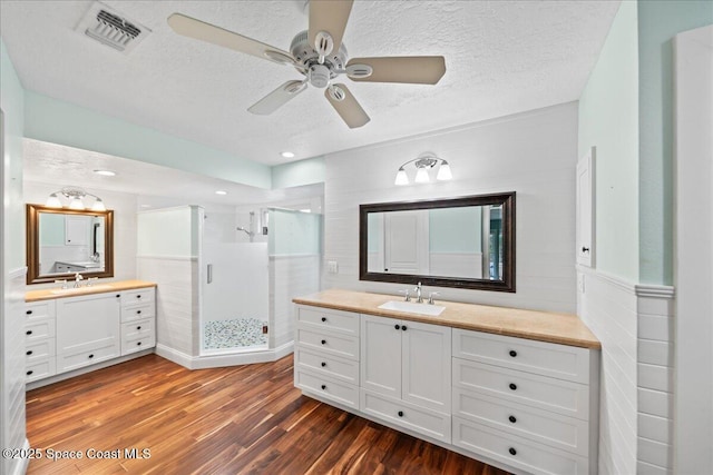 6345 Anchor Ln, Rockledge, FL 32955 - bathroom with wood finished floors, a stall shower, ceiling fan, two vanities, and a textured ceiling