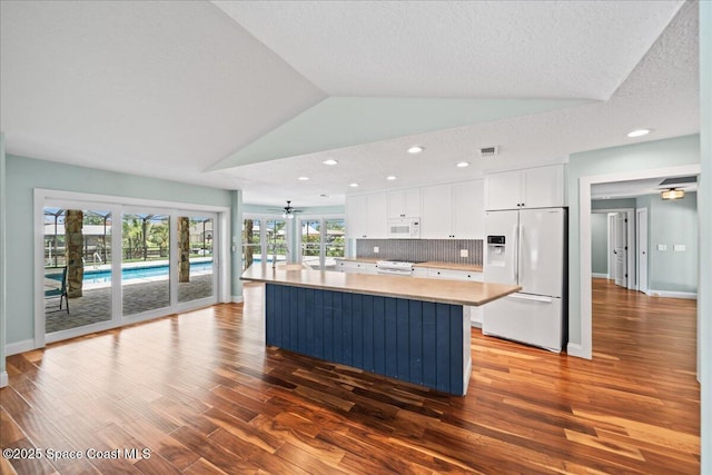 6345 Anchor Ln, Rockledge, FL 32955 - kitchen with white appliances, wood finished floors, lofted ceiling, a kitchen island with sink, and white cabinetry