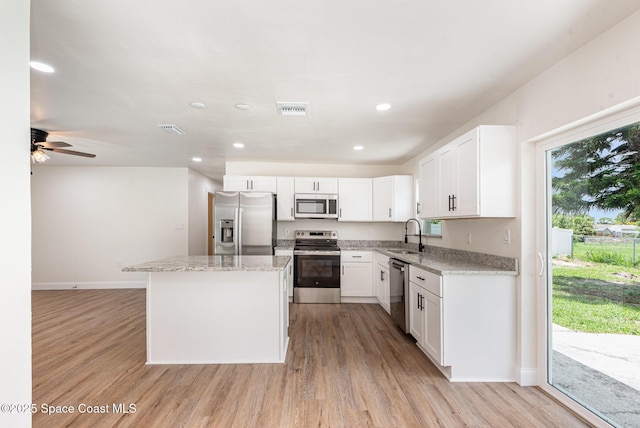 878 Iroquois Ave, Melbourne, FL 32935 - kitchen with appliances with stainless steel finishes, baseboards, a kitchen island, light wood-type flooring, and recessed lighting
