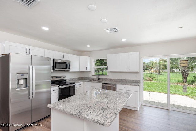 878 Iroquois Ave, Melbourne, FL 32935 - kitchen featuring appliances with stainless steel finishes, a sink, a kitchen island, white cabinetry, and light stone countertops