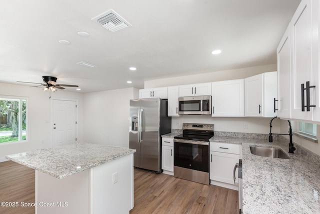 878 Iroquois Ave, Melbourne, FL 32935 - kitchen with appliances with stainless steel finishes, a sink, light wood finished floors, recessed lighting, and white cabinets