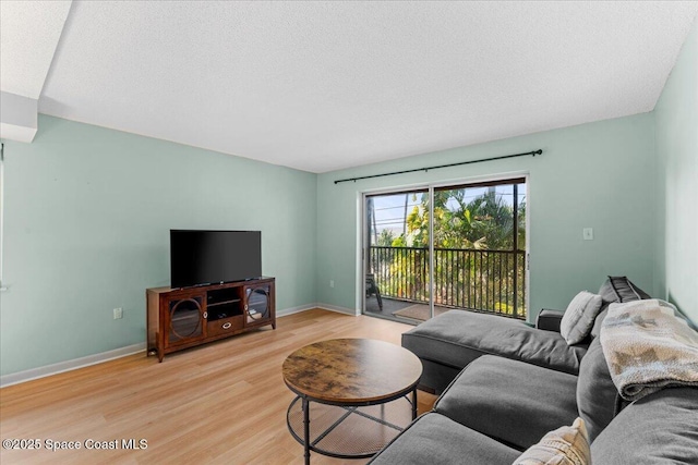 living area featuring light wood-style flooring, baseboards, and a textured ceiling