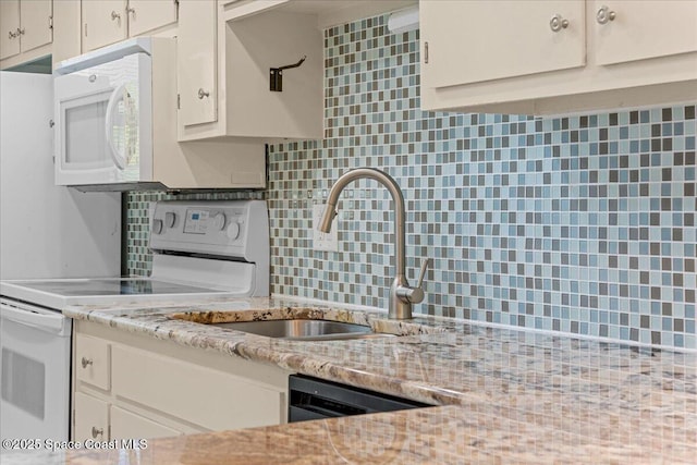 kitchen featuring white appliances, backsplash, a sink, and white cabinets