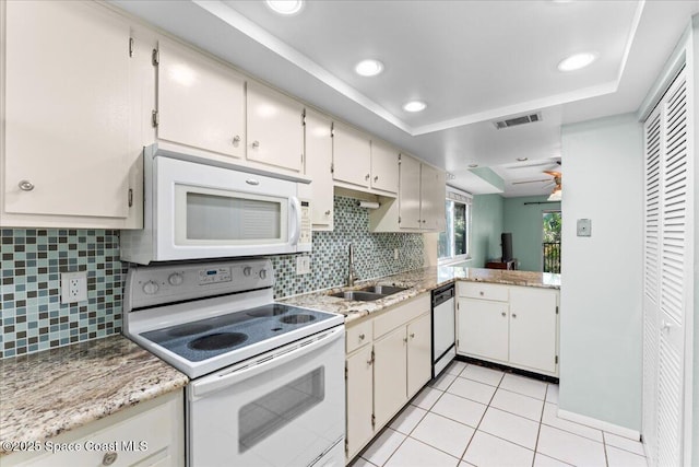 kitchen with white appliances, a sink, decorative backsplash, a raised ceiling, and light tile patterned floors