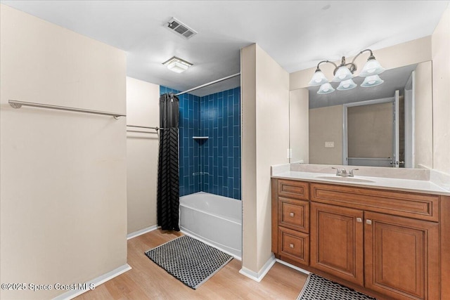 bathroom featuring wood finished floors, baseboards, shower / bathtub combination with curtain, and vanity