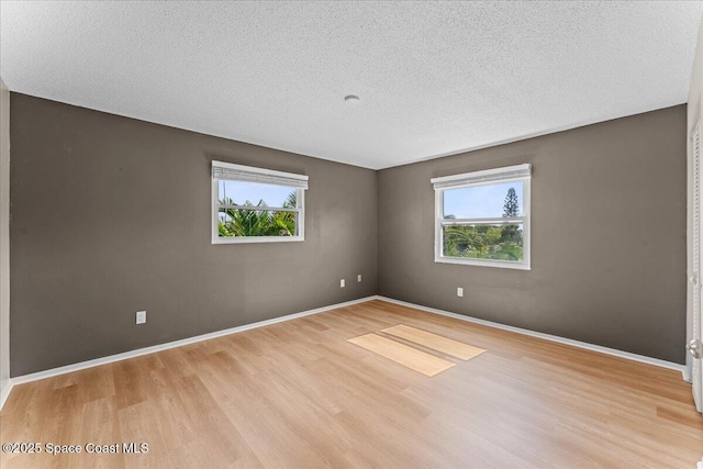 unfurnished room featuring light wood finished floors, a textured ceiling, and baseboards