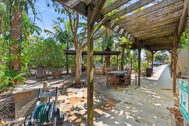 view of patio with exterior kitchen, a pergola, and outdoor dining space