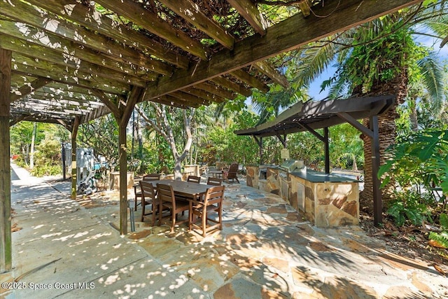 view of patio with an outdoor kitchen, a pergola, and outdoor dining space