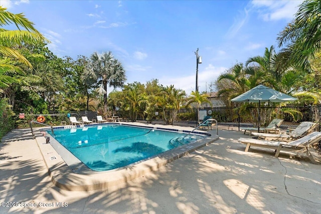 community pool with fence and a patio