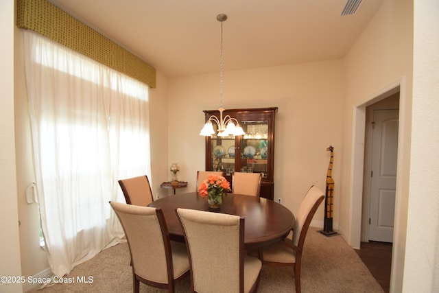 carpeted dining area featuring a chandelier