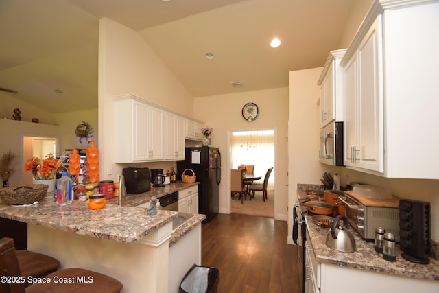 kitchen featuring appliances with stainless steel finishes, lofted ceiling, a peninsula, white cabinets, and a breakfast bar area