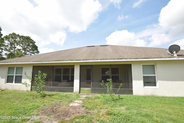back of property with a sunroom, a yard, and stucco siding