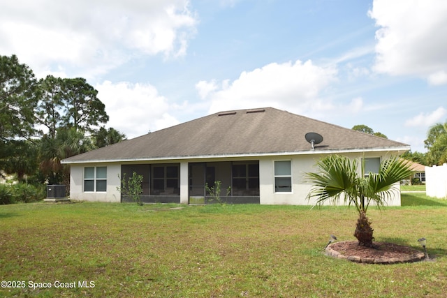 rear view of property featuring a sunroom, stucco siding, a lawn, and central AC unit