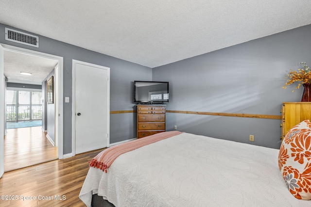 55 Riverside Dr Unit 103, Cocoa, FL 32922 - bedroom with a textured ceiling, wood finished floors, and baseboards