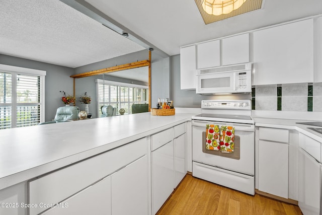 55 Riverside Dr Unit 103, Cocoa, FL 32922 - kitchen featuring white appliances, light countertops, light wood-type flooring, white cabinets, and plenty of natural light