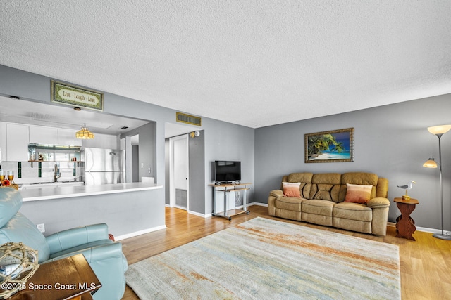 55 Riverside Dr Unit 103, Cocoa, FL 32922 - living area featuring light wood-style floors, a textured ceiling, and baseboards