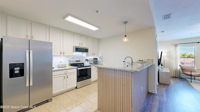4047 Meander Pl Unit 205, Rockledge, FL 32955 - kitchen with appliances with stainless steel finishes, tasteful backsplash, white cabinets, a peninsula, and light stone countertops