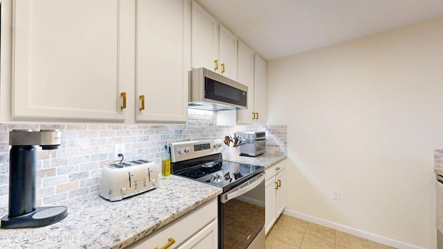 4047 Meander Pl Unit 205, Rockledge, FL 32955 - kitchen with appliances with stainless steel finishes, backsplash, light stone countertops, baseboards, and white cabinets