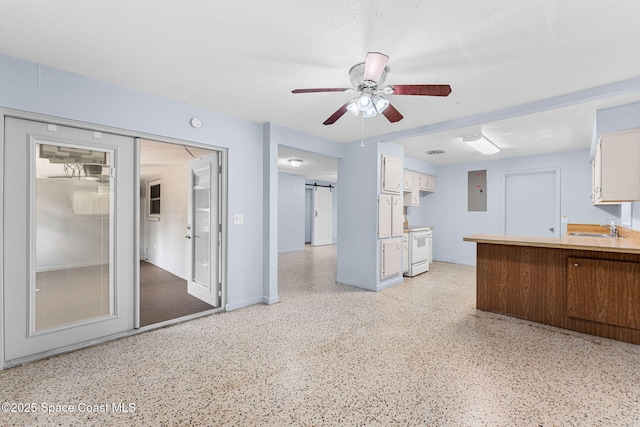 unfurnished living room featuring a sink, dark aggregate flooring, a ceiling fan, and electric panel