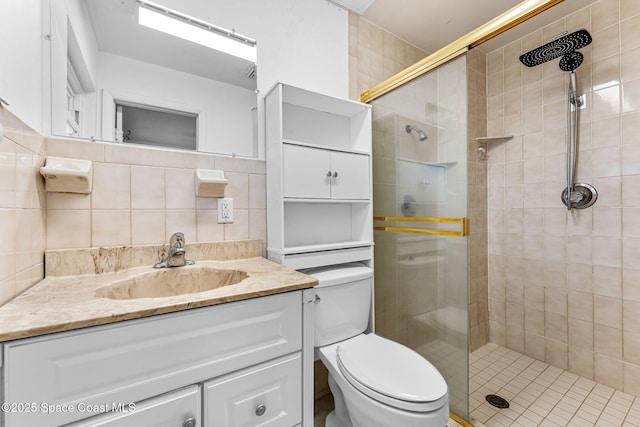 full bath with a stall shower, toilet, vanity, and tile walls