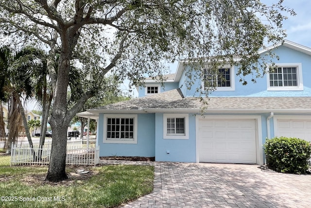 view of front of home with stucco siding, a garage, decorative driveway, fence, and a shingled roof