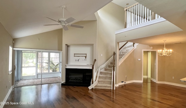unfurnished living room with stairs, high vaulted ceiling, wood finished floors, ceiling fan, and a fireplace with raised hearth