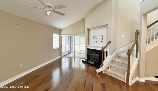 living area featuring high vaulted ceiling, wood finished floors, ceiling fan, stairway, and baseboards