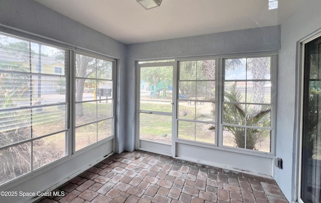 unfurnished sunroom with plenty of natural light and brick floors