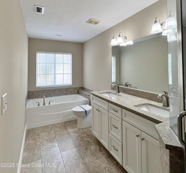 full bathroom with a garden tub, double vanity, a textured ceiling, and toilet