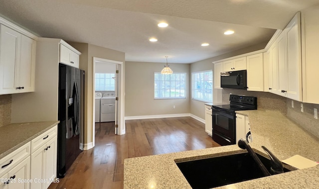 kitchen featuring black appliances, washer and clothes dryer, a sink, dark wood finished floors, and white cabinets