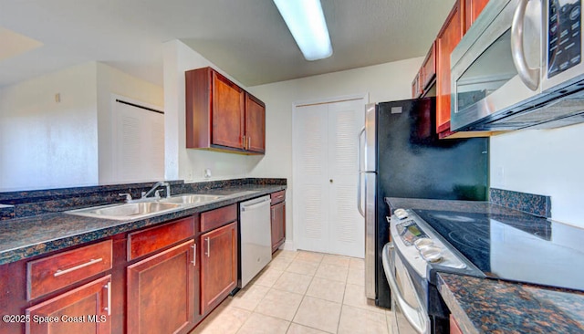 kitchen with stainless steel appliances, a sink, reddish brown cabinets, and light tile patterned flooring