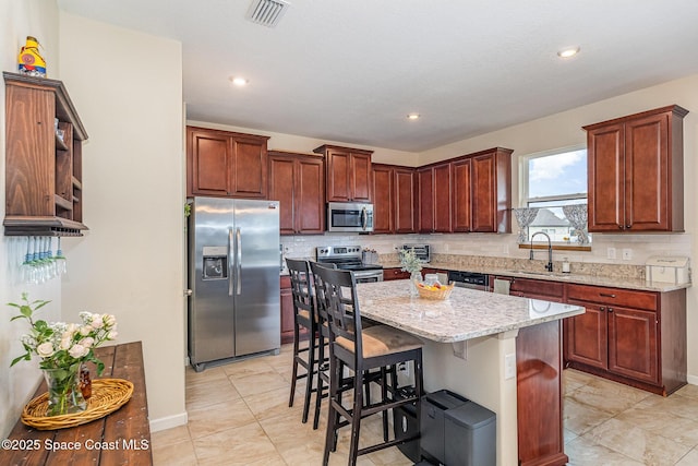4109 Alligator Flag Cir, West Melbourne, FL 32904 - kitchen featuring appliances with stainless steel finishes, a sink, a breakfast bar, light stone countertops, and a kitchen island