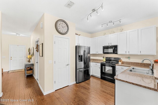 2650 Revolution St Unit 103, Melbourne, FL 32935 - kitchen with black appliances, a sink, wood finished floors, white cabinets, and baseboards